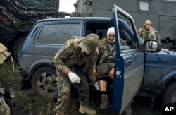 A Ukrainian soldier helps his wounded fellow soldier on the road in the freed territory of the Kharkiv region, Ukraine, on September 12, 2022. (Kostiantyn Liberov/AP)