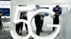 FILE - Visitors wearing mask to protect from the coronavirus walk past a 5G sign at the China Beijing International High Tech Expo in Beijing, China on Sept. 17, 2020. 