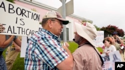 FILE - Anti-abortion activist Doug Lane, right, is confronted by abortion-rights supporter John Osborne and other sign-carrying supporters outside the Jackson Women's Health Organization clinic in Jackson, Miss., July 6, 2022.