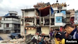 People survey a site damaged by an earthquake, in Kathmandu, Nepal, April 25, 2015. 