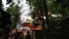 People look on a house engulfed in flames in Sittwe, Burma, June 11, 2012.