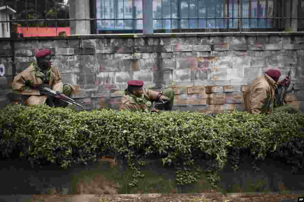 Kenya security forces are seen behind a wall outside the Westgate Mall in Nairobi, Sept. 23, 2013.