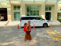 រូប​ឯកសារ៖ ស្ត្រីពីរ​នាក់​ដើរ​កាត់រថយន្តលោកនាយករដ្ឋមន្ត្រី ហ៊ុន សែន នៅមន្ទីរពេទ្យកាល់ម៉ែត រាជធានីភ្នំពេញ កាលពីខែមីនា ឆ្នាំ២០២១។ (អូន ឆេងប៉រ/វីអូអេ)