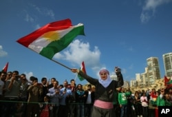 Suriah Kurd Nazdan, yang melarikan diri dari rumahnya di Qamishli, Suriah, mengenakan pakaian tradisional saat ia menari dan mengibarkan bendera Kurdi, selama perayaan hari Nowruz, di Beirut, Lebanon, 21 Maret 2016. (Foto: AP)
