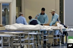 Petugas medis memeriksa jenazah di Kantor Pemeriksaan Medis Orlando (12/6).