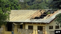 FILE - A woman stands outside a damaged school dormitory after it was set on fire in Bafut, in the Northwest English-speaking region of Cameroon, Nov. 15, 2017. 