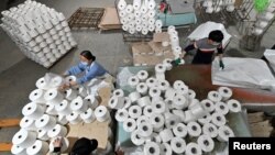 Para pekerja terlihat di lini produksi di sebuah pabrik tekstil kapas di Korla, Daerah Otonomi Uighur Xinjiang, China 1 April 2021. (Foto: cnsphoto via REUTERS)