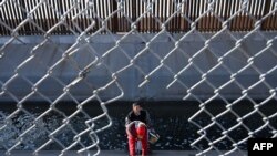 Porodica migranata iz Kolumbije penje se kroz ogradu kanala nakon što je prešla kroz rupu u zidu granice između SAD i Meksika u El Pasu, Teksas, 19. decembra 2022.