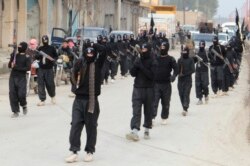 FILE - Islamic State of Iraq and the Levant fighters carry their weapons during a parade at the Syrian town of Tel Abyad, near the border with Turkey, Jan. 2, 2014.