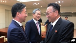 In this photo provided by the South Korean Unification Ministry, Unification Minister Hong Yong-pyo, left, shakes hands with Kim Yang Gon, a senior North Korean official responsible for South Korean affairs, after their meeting at Panmunjom, Aug. 25, 2015.