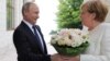 Russian President Vladimir Putin welcomes German Chancellor Angela Merkel during their meeting in the Black Sea resort of Sochi, Russia, May 18, 2018. 