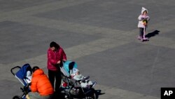 Sejunmlah warga tampak membawa bayinya ke sebuah taman di Beijing, China, pada 17 Februari 2019. (Foto: AP/Andy Wong)