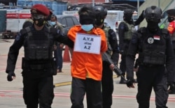 FILE - Police escort a suspected militant at Soekarno-Hatta International Airport in Tangerang, Indonesia, March 18, 2021. Suspected militants arrested in raids at that time were believed to be connected to Jemaah Islamiyah extremists.