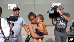 Adalicia Montecino and her husband Rolando Bueso Castillo are surrounded by the media as they walk with their year-old son Johan Bueso Montecinos, who became a poster child for the U.S. policy of separating immigrants and their children, in San Pedro Sula, Honduras, Friday, 20, 2018.