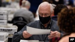 Para pejabat Komisi Pemilihan Cobb County menghitung surat suara secara manual untuk audit, di Marietta, Georgia, 16 November 2020. 