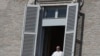 Pope Francis leans out of his studio window overlooking St. Peter's Square at the Vatican, March 15, 2020. 