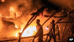 FILE - People walk by U.N. vehicles which were set on fire, in Goma, Democratic Republic of Congo, Nov. 1, 2022. 