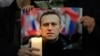 Para pengunjuk rasa memegang foto Alexey Navalny saat melakukan demonstrasi di seberang Kedutaan Besar Rusia di London, Jumat, 16 Februari 2024. (Foto: AP)