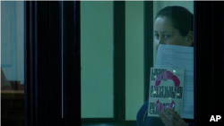 While in a Georgian courtroom on Jan. 14, 2025, journalist Mzia Amaglobeli holds up the book "How to Stand Up to a Dictator" by Nobel laureate Maria Ressa.