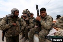 FILE - Kurdish People's Protection Units (YPG) fighters carry their weapons while riding on the back of a pick-up truck in Qamishli, Syria, March 11, 2016.