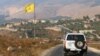 Mobil Penjaga Perdamaian PBB melintas di depan bendera Hizbullah di desa Khiam, perbatasan Lebanon dan Israel, 28 Juli 2020. 