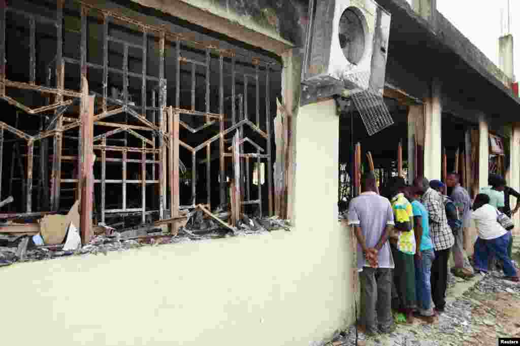 Mahalliy aholi vakillari Mpeketonida jangarilar vayron qilgan binolarni ko&#39;zdan kechirmoqda, 16-iyun, 2014-yil.
