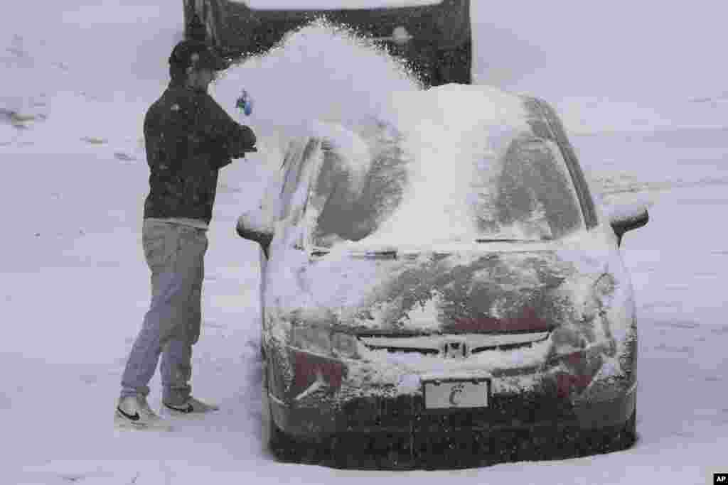 A person dusts snow off of a car during a winter storm, Jan. 5, 2025, in Cincinnati, Ohio.