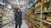 A shopper wearing a face mask browses an aisle of cooking oil in a supermarket in Beijing on March 16, 2020. 