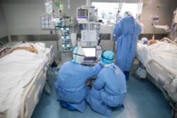 Medical staff treat COVID-19 coronavirus patients at a hospital in Wuhan, in China's central Hubei province, March 19, 2020.