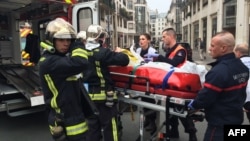 FILE - Firefighters carry an injured man on a stretcher in front of the offices of the French satirical newspaper Charlie Hebdo in Paris, Jan. 7, 2015, after armed gunmen stormed the offices, killing 12.