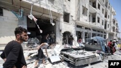 FILE - Syrians gather at a site of car bomb in the northwestern Syrian city of Idlib, Aug. 2, 2018. 