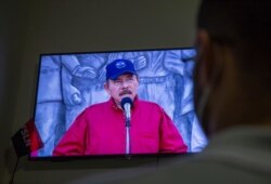 A man watches a televised national address by Nicaraguan President Daniel Ortega, at his home in Managua, June 23, 2021.