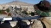 A Houthi militant sits guard on the roof of a building overlooking fellow Houthis rallying to denounce the rapid devaluation of the Yemeni Rial in Sanaa, Yemen, Oct. 5, 2018.