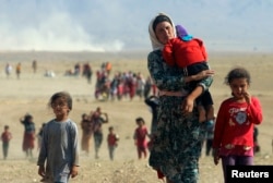 FILE - Yazidis, displaced within Iraq and fleeing violence from forces loyal to the Islamic State group, are seen heading toward the Syrian border, Aug. 11, 2014.