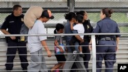Ever Castillo, left, and his family, immigrants from Honduras, are escorted back across the border by U.S. Customs and Border Patrol agents, June 21, 2018, in Hildalgo, Texas. The parents were told they would be separated from their children.