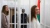 Journalists Katsiaryna Andreyeva, right, and Daria Chultsova stand inside a defendants' cage in a court room in Minsk, Belarus, Feb. 18, 2021. 