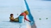 A woman paints the floor of a pool as her child pulls at her saree in Delhi, India.