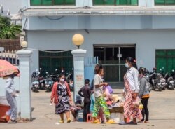 Garment factory workers wear face masks as they walk out at the end of their work shift in Phnom Penh, Cambodia, April 3, 2020. (Hean Socheata/VOA Khmer)