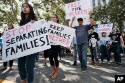 Protesters carry signs and chant slogans in front of the federal courthouse in Los Angeles, June 26, 2018.