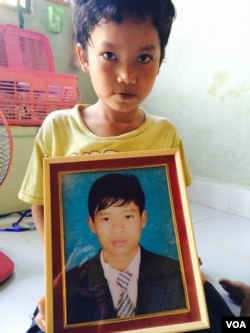 Pheng Panha, who lost his older brother one year ago, shown here with his sibling's portrait at home in Phnom Penh's Dangko district.