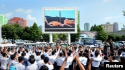 Orang-orang menonton melalui layar besar yang menunjukkan peluncuran uji rudal balistik antar benua Hwasong-14 dalam foto yang dirilis oleh Kantor Berita Pusat Korea Korea Utara (KCNA), 5 Juli 2017.