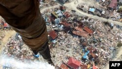 Disinfektan dilepaskan di suatu daerah di Palu yang terkena likuifaksi akibat gempa bumi 28 September dan di mana ribuan orang masih dikhawatirkan terkubur, 18 Oktober 2018. Aksi itu dilakukan untuk mensterilkan daerah terdampak.(Foto: AFP)