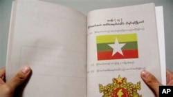 In this photo released by China's Xinhua News Agency, a citizen holds a copy of the Myanmar constitution draft in Yangon, Myanmar, Thursday, April 10, 2008. Myanmar has been launching an official campaign, distributing eight kinds of promotion leaflets to