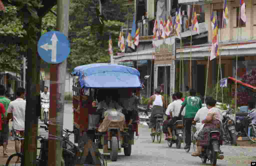 Vehicles drive on a road as Buddhist flags are displayed outside a religious building in Thandwe, Rakhine State, western Burma, Oct. 2, 2013. 