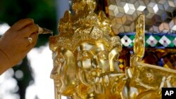 FILE - A Brahmin priest anoints Phra Phrom, the Thai interpretation of the Hindu god Brahma, with holy water during wellness and prosperity ceremony in Bangkok, Thailand, Friday, Sept. 4, 2015.