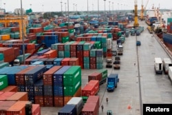FILE- Workers are seen among the containers at Asia World port in Yangon, Myanmar, July 2, 2014.
