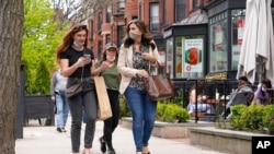 Sejumlah pejalan kaki berjalan di Newsbury Street, Boston, 2 Mei 2021. CDC mengatakan orang yang sudah vaksinasi COVID-19 dosis lengkap tak perlu pakai masker.