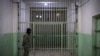 FILE - A member of the Syrian Democratic Forces stands guard in a prison where men suspected to be affiliated with the Islamic State are jailed in northeast Syria in the city of Hasakeh, Oct. 26, 2019.