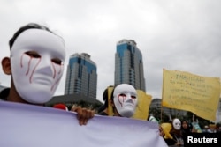 Para wartawan Indonesia mengenakan topeng saat mengikut pawai Hari Buruh di Museum Nasional (Monas), Jakarta, 1 Mei 2019. (Foto: Reuters)