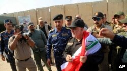 Perdana Menteri Irak Haider al-Abadi, tengah, berselimut bendera Irak di Mosul, Irak, 9 Juli 2017. 